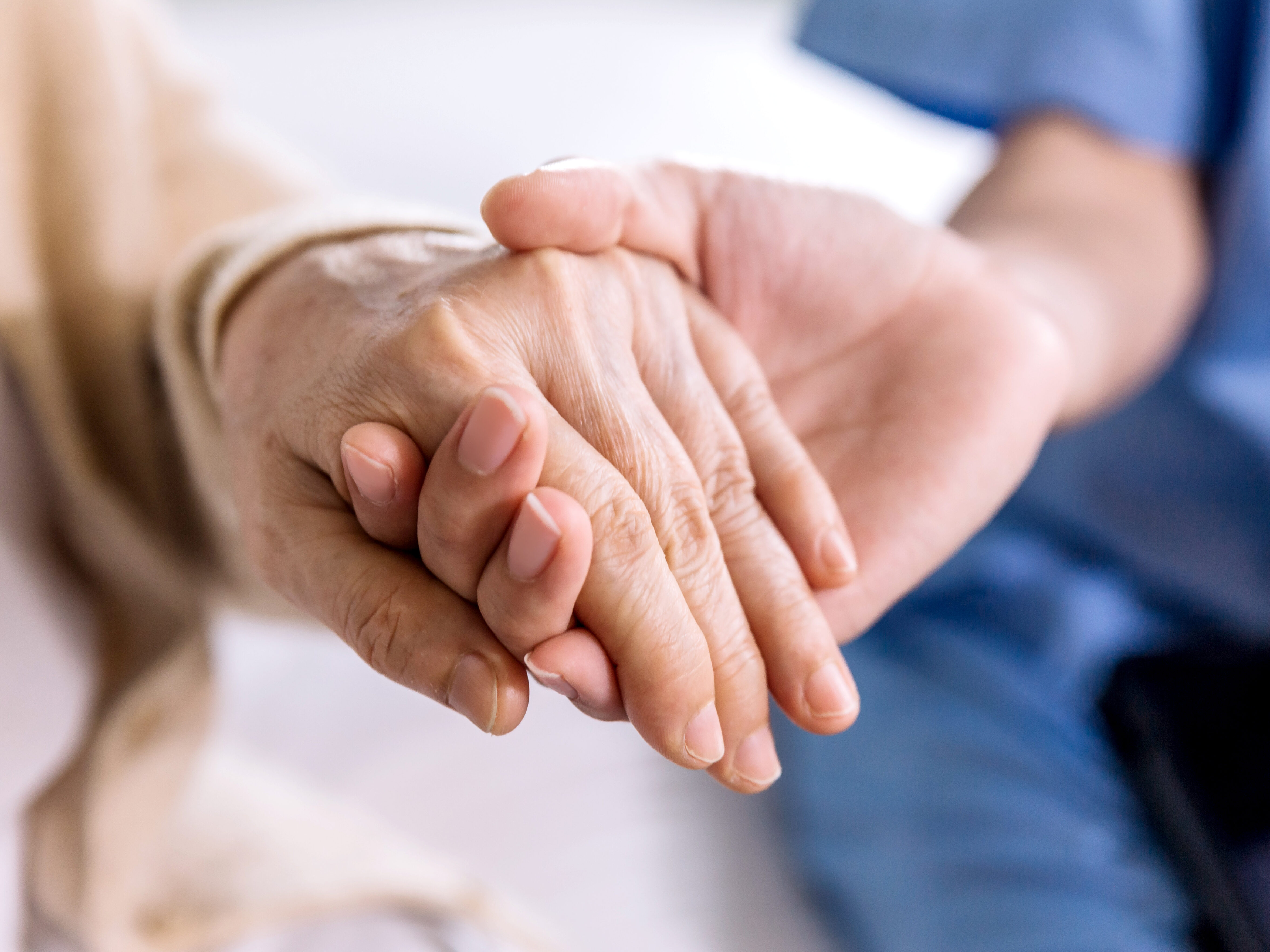Close-up senior Asian woman hand with her caregiver helping hands holding together, Caregiver visit at home. Home health care and nursing home concept.